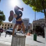 Athletic woman performing handstand on bin in the city
